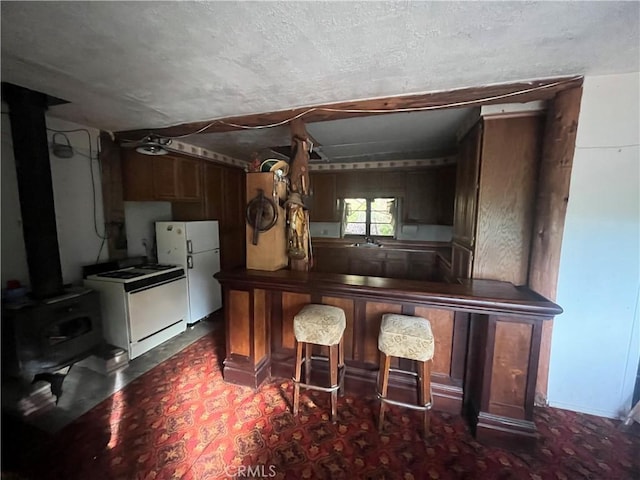 kitchen with stove, freestanding refrigerator, and a wood stove