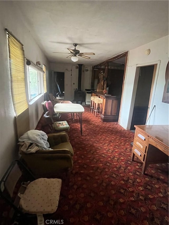 living area with carpet flooring, a wood stove, and a ceiling fan