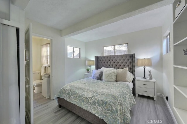 bedroom with light wood-type flooring and ensuite bath