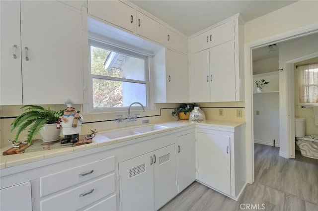 kitchen with white cabinets, decorative backsplash, and sink