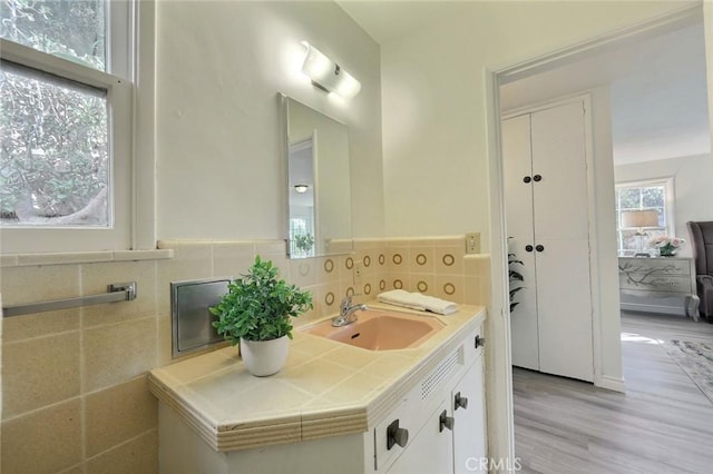 bathroom with hardwood / wood-style flooring, vanity, and tile walls