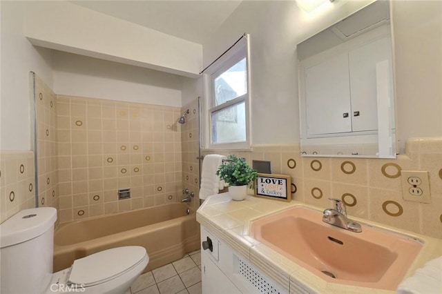 full bathroom featuring vanity, tiled shower / bath, tile patterned flooring, toilet, and tile walls