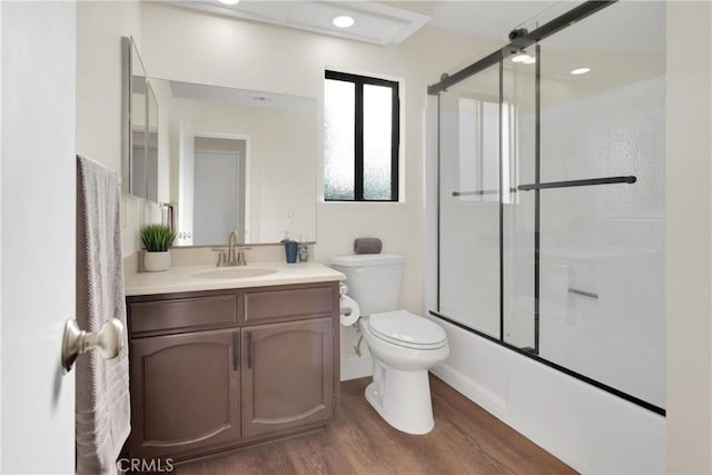 full bathroom featuring toilet, vanity, bath / shower combo with glass door, and hardwood / wood-style flooring