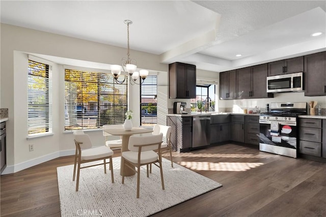 kitchen featuring sink, an inviting chandelier, dark brown cabinetry, pendant lighting, and appliances with stainless steel finishes