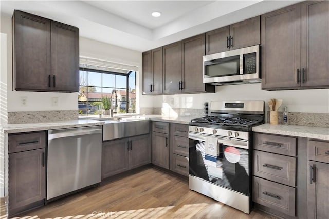 kitchen featuring light hardwood / wood-style floors, stainless steel appliances, dark brown cabinets, and sink