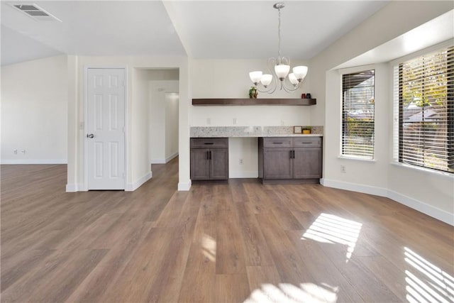 kitchen with wood-type flooring, a chandelier, dark brown cabinets, and hanging light fixtures