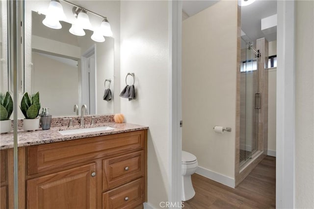 bathroom featuring wood-type flooring, walk in shower, vanity, and toilet