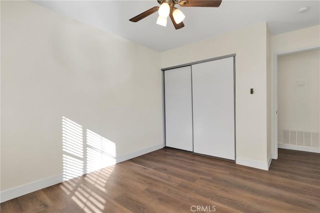 unfurnished bedroom featuring ceiling fan, dark wood-type flooring, and a closet