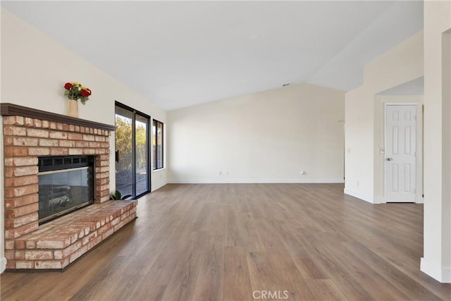 unfurnished living room featuring a brick fireplace, vaulted ceiling, and hardwood / wood-style floors