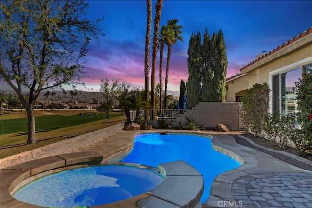 pool at dusk with an in ground hot tub