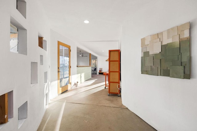 hall featuring concrete flooring and plenty of natural light