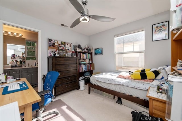 carpeted bedroom with ensuite bath and ceiling fan