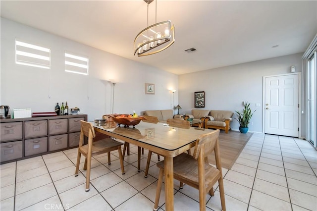 dining space featuring light tile patterned floors and a notable chandelier