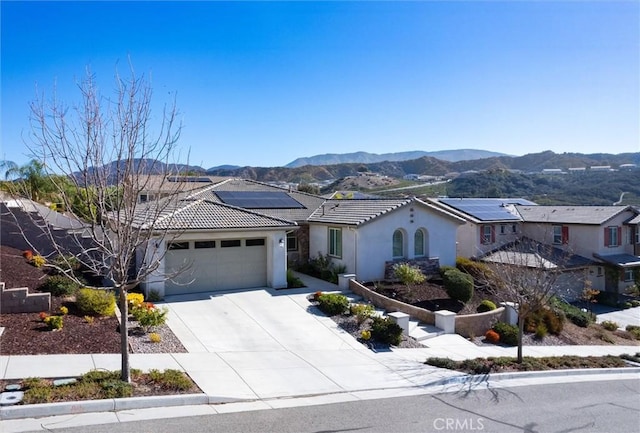 view of front facade with a garage, a mountain view, and solar panels