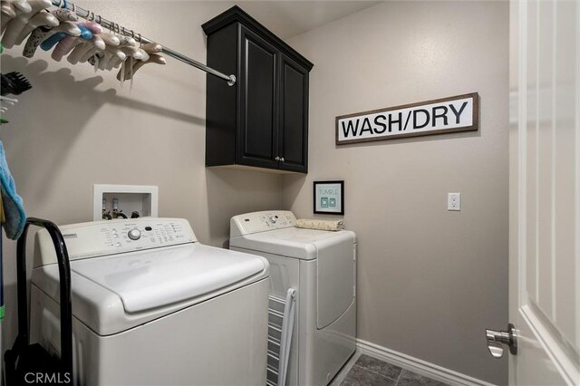 clothes washing area with dark tile patterned flooring, cabinets, and washing machine and clothes dryer