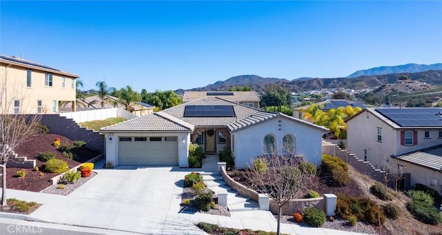 view of front facade featuring a mountain view, a garage, and solar panels