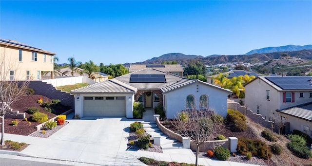 view of front facade with a garage, a mountain view, and solar panels