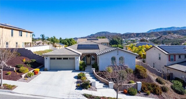 view of front of home featuring a mountain view, a garage, and solar panels