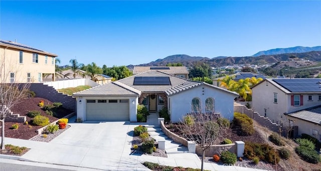 mediterranean / spanish home featuring a mountain view, a garage, solar panels, a tile roof, and concrete driveway