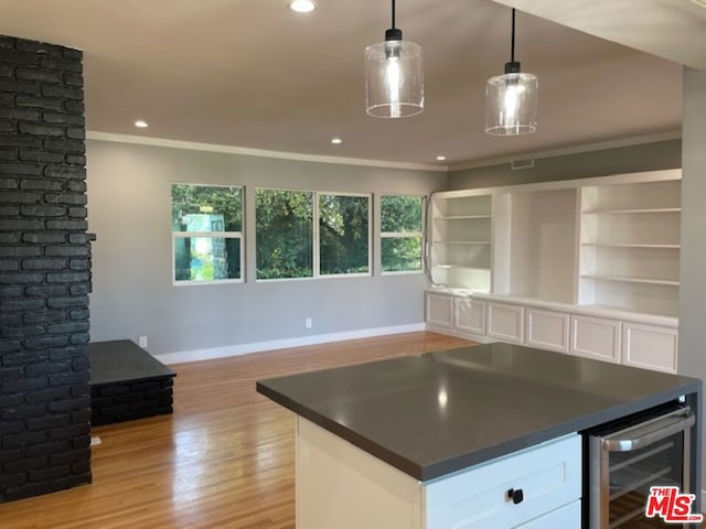 kitchen with wine cooler, decorative light fixtures, light hardwood / wood-style floors, ornamental molding, and white cabinets