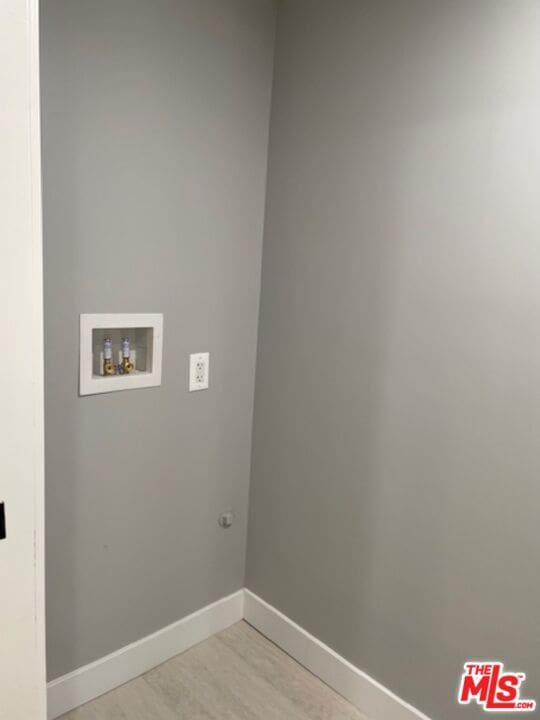 clothes washing area with washer hookup and light wood-type flooring