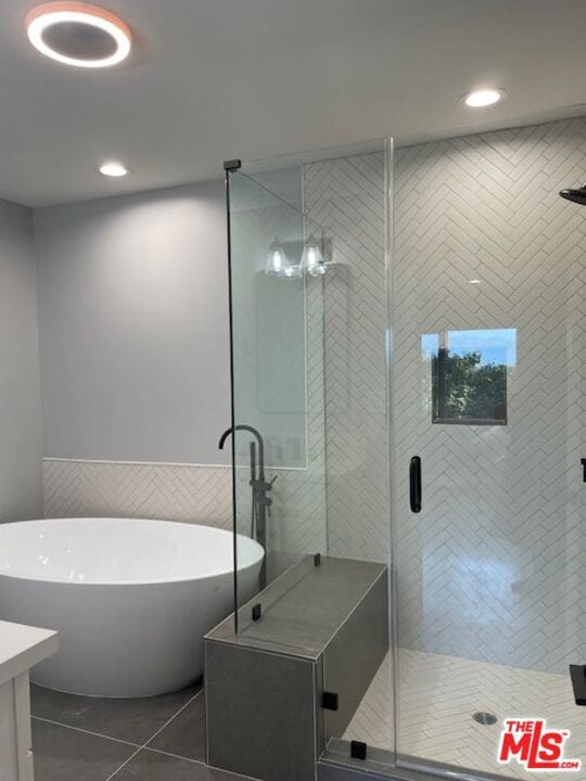 bathroom featuring separate shower and tub, vanity, tile patterned flooring, and tile walls