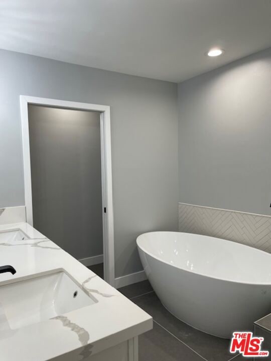 bathroom with a tub, tile patterned flooring, and vanity