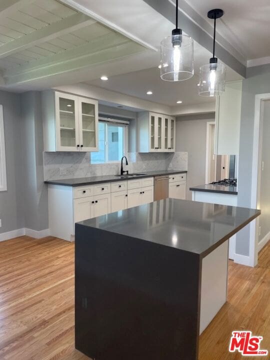 kitchen with decorative backsplash, sink, white cabinetry, hanging light fixtures, and light wood-type flooring