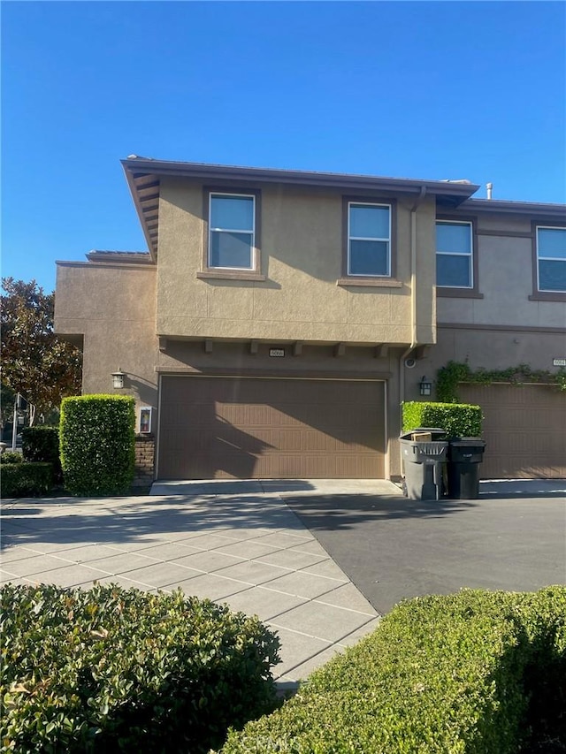 view of front of home with driveway, an attached garage, and stucco siding