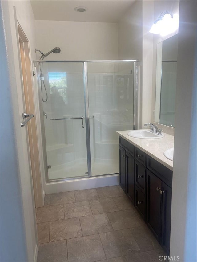 bathroom featuring double vanity, a sink, and a shower stall