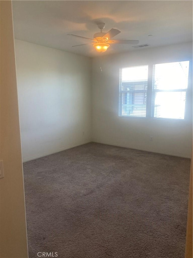 spare room featuring carpet floors, ceiling fan, and visible vents