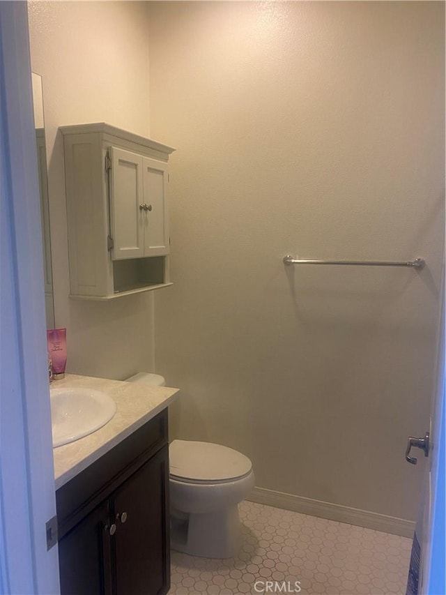 bathroom with toilet, vanity, and baseboards