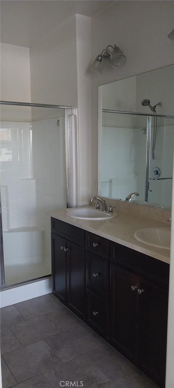 full bathroom featuring double vanity, a stall shower, and a sink