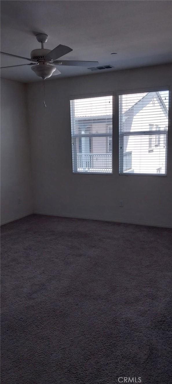 unfurnished room with a ceiling fan, carpet, visible vents, and a healthy amount of sunlight