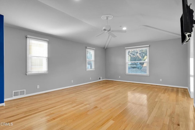 spare room featuring a wealth of natural light, ceiling fan, lofted ceiling, and light wood-type flooring