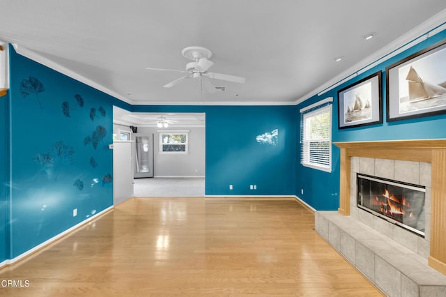 unfurnished living room featuring a tile fireplace, crown molding, light hardwood / wood-style flooring, and ceiling fan