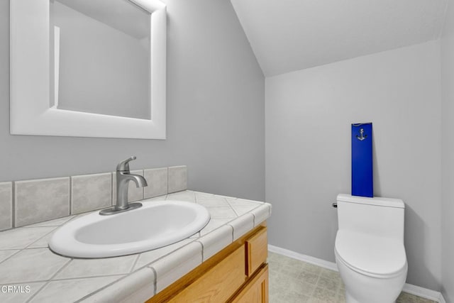 bathroom with vanity, vaulted ceiling, and toilet