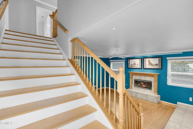 stairway featuring a tiled fireplace, ceiling fan, and hardwood / wood-style flooring