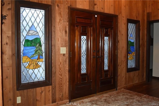 foyer entrance featuring hardwood / wood-style floors and wooden walls