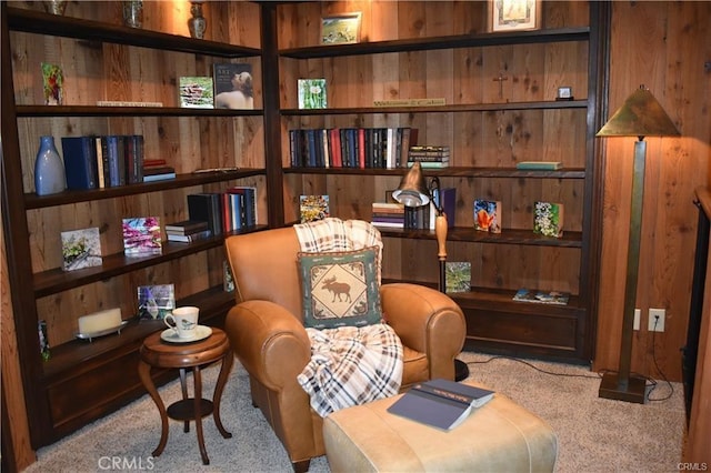 sitting room featuring light carpet and wood walls