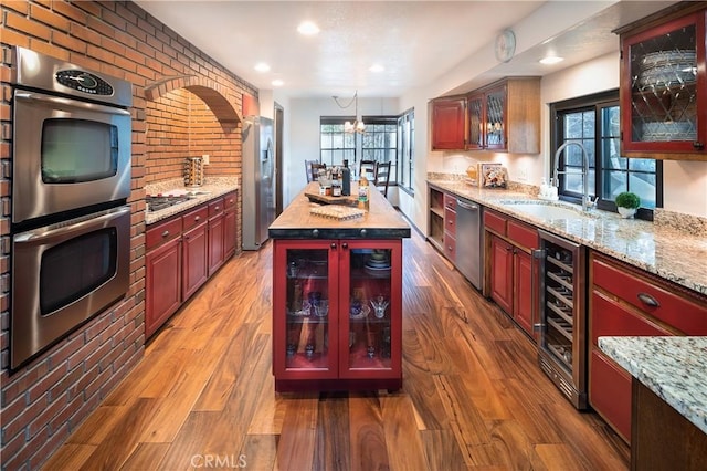 kitchen featuring pendant lighting, sink, wood-type flooring, and appliances with stainless steel finishes