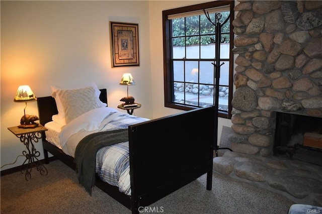 bedroom featuring carpet and a stone fireplace