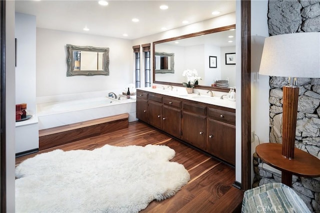 bathroom with a tub to relax in, vanity, and wood-type flooring