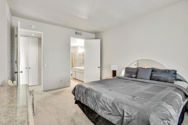 bedroom featuring connected bathroom and light colored carpet