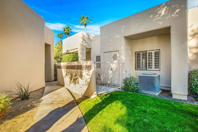 view of exterior entry featuring central AC and a yard