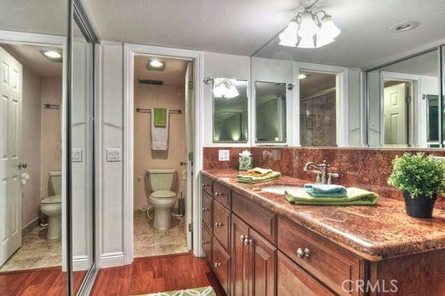 full bathroom with toilet, backsplash, wood finished floors, and vanity