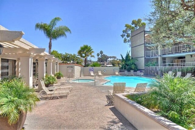 pool with a patio area, fence, and a hot tub