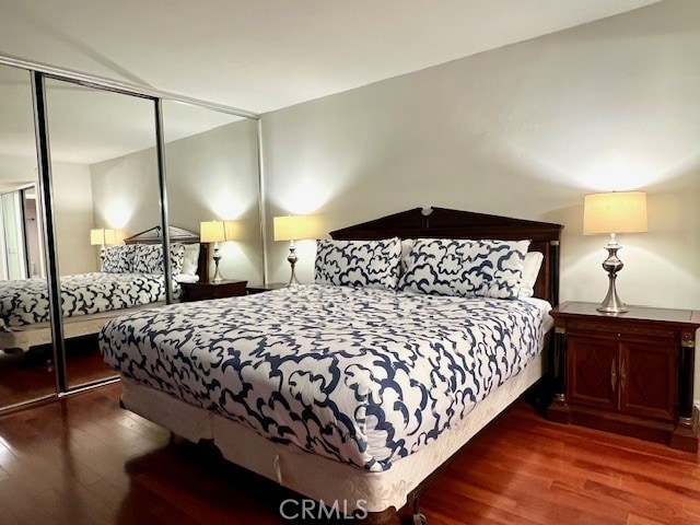 bedroom with dark wood-type flooring and a closet