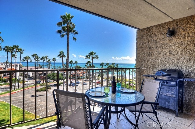 balcony with a water view, grilling area, and a view of the beach