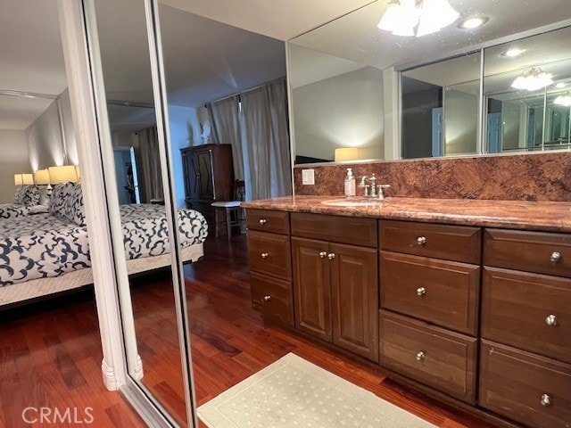 bathroom featuring tasteful backsplash, wood finished floors, vanity, and ensuite bathroom